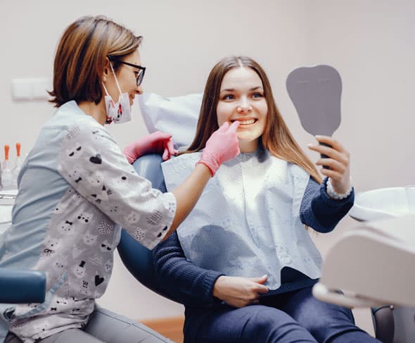 Two women in casual clothing applying makeup together indoors during a beauty consultation.
