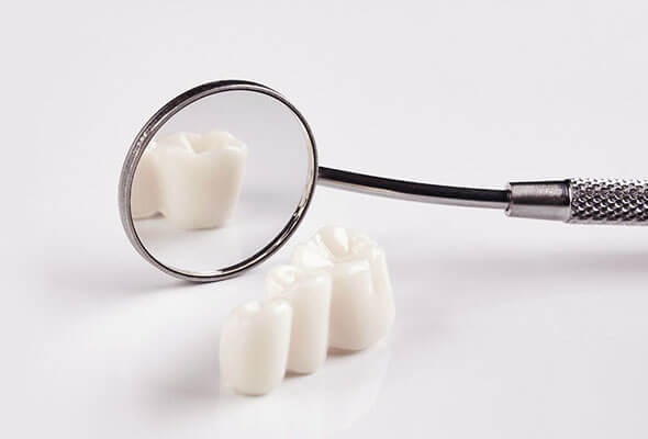 Magnifying glass examining white dental implants or crowns on white background.