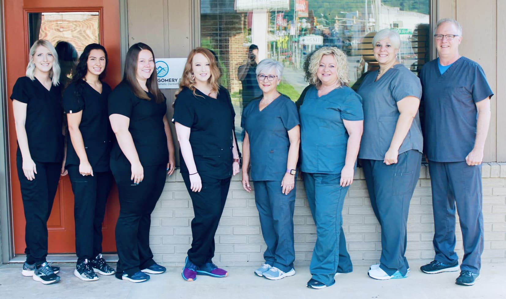 Team of healthcare professionals in scrubs standing together in clinical hallway setting.